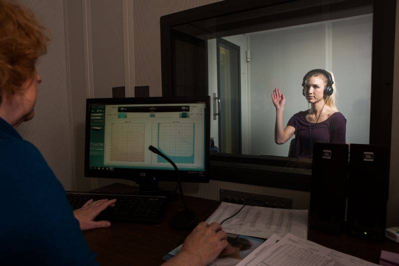This is an image of faculty performing a hearing screening in the audiology booth.